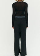 Model wearing a black outfit with sheer top and wide-leg stripe pants on a white background