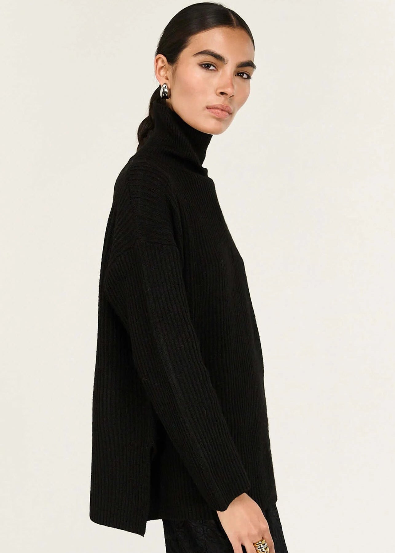 Person wearing a black turtleneck and black lace dress on a white background