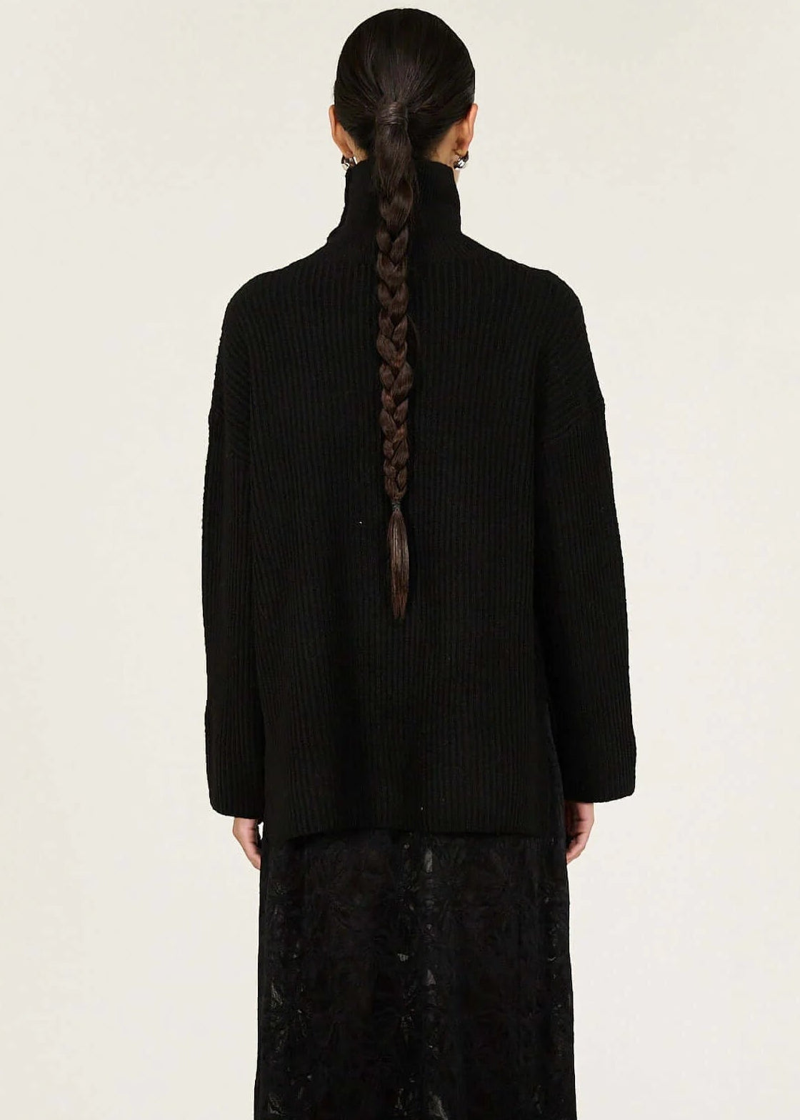 Person wearing a black turtleneck and black lace dress on a white background