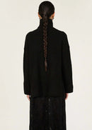 Person wearing a black turtleneck and black lace dress on a white background