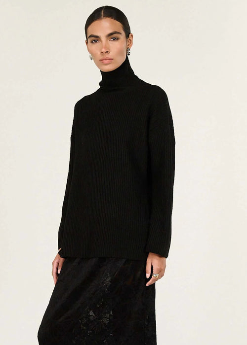 Woman wearing a black turtleneck and black skirt on a white background
