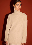 Woman wearing a beige turtleneck sweater against a red background