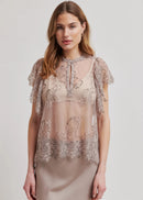 Woman wearing a sheer lace top with a plain background