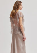 Woman wearing a sheer lace top with a plain background