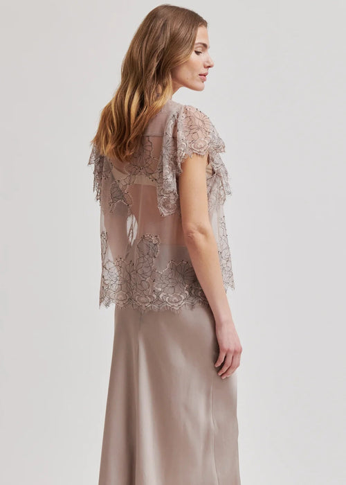 Woman wearing a sheer lace top with a plain background