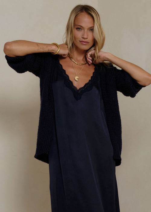 Woman wearing a navy cardigan on grey background