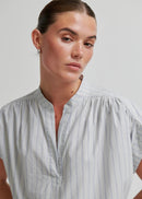 Woman wearing a light grey striped shirt against a plain background
