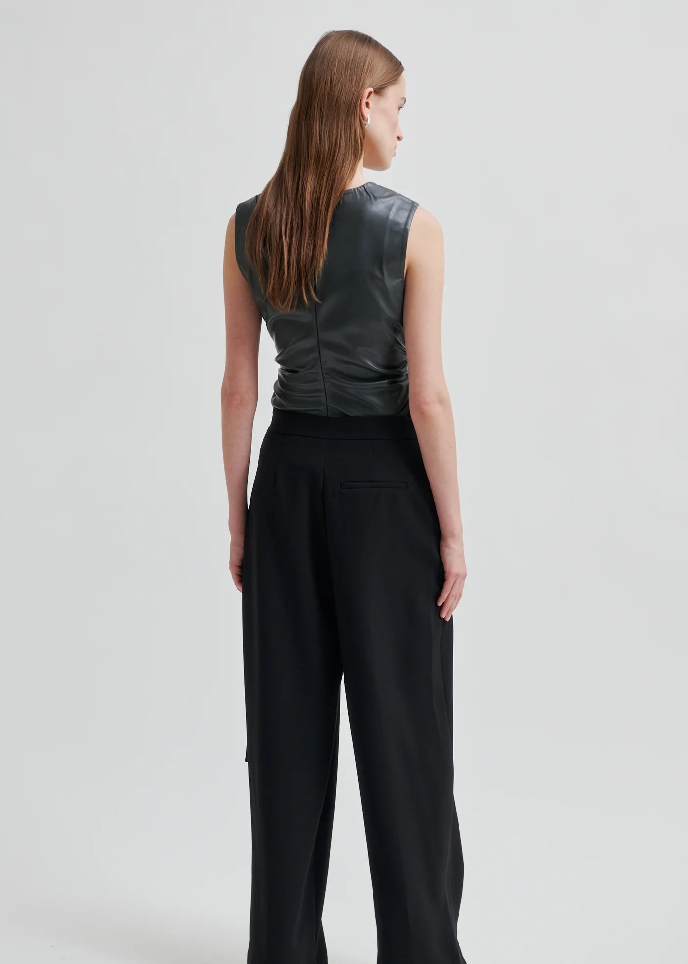 Woman wearing a dark grey sleeveless top on a light grey background