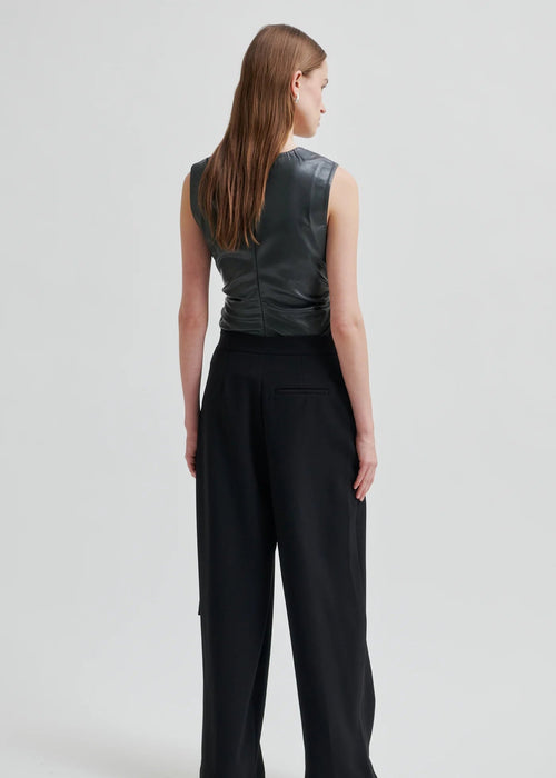 Woman wearing a dark grey sleeveless top on a light grey background