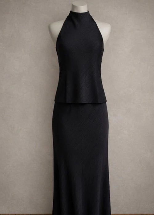 A sleeveless high-neck black top displayed on a white mannequin torso against a textured grey studio background.