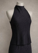 A sleeveless high-neck black top displayed on a white mannequin torso against a textured gray studio background.