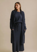 Woman wearing a navy blue cardi with a belt against a beige background