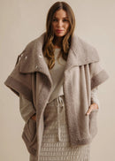 Woman wearing a beige fleece-lined jacket against a neutral background