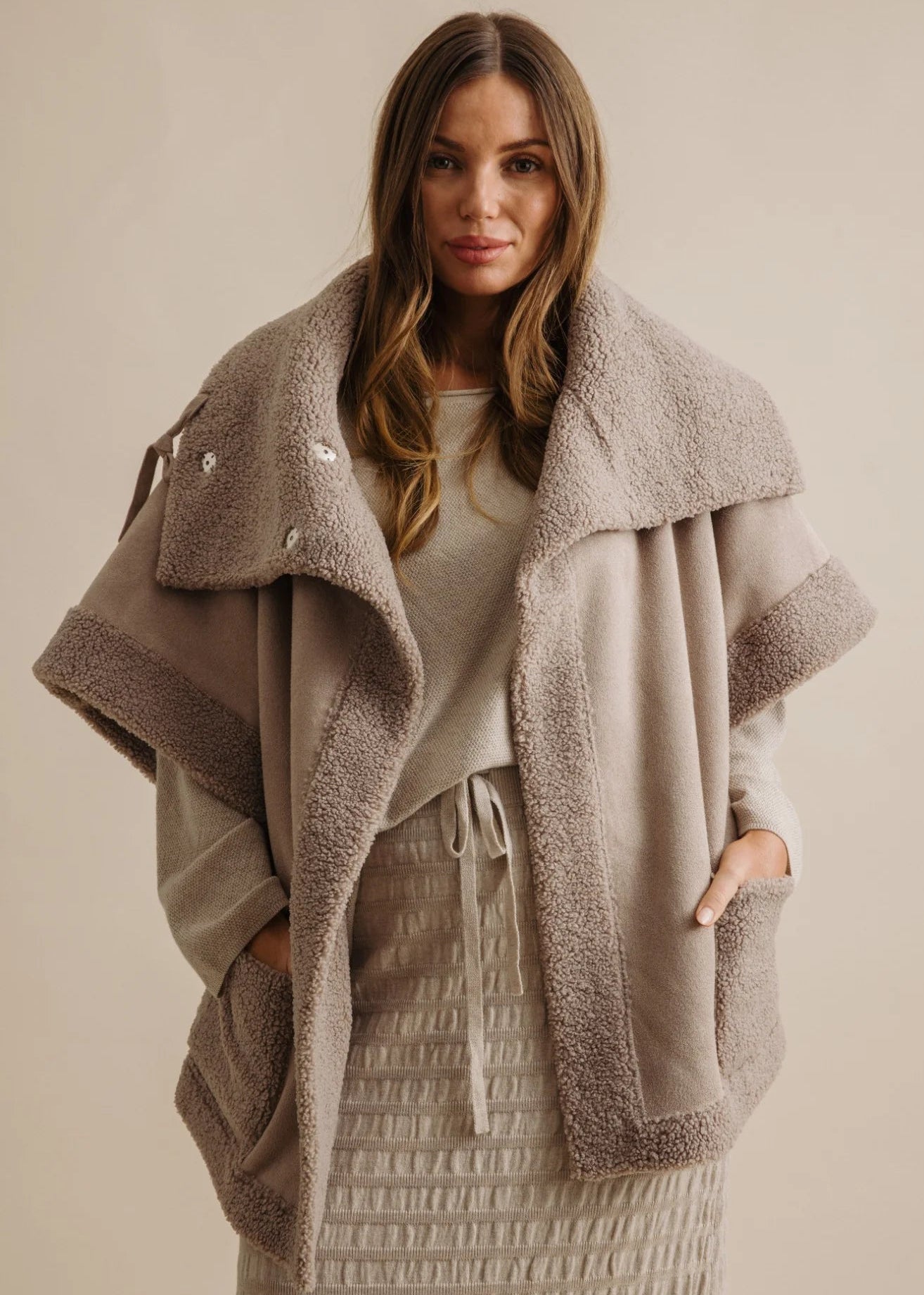 Woman wearing a beige fleece-lined jacket against a neutral background