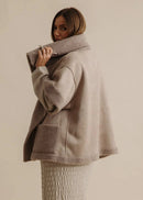 Woman wearing a beige fleece-lined jacket against a neutral background