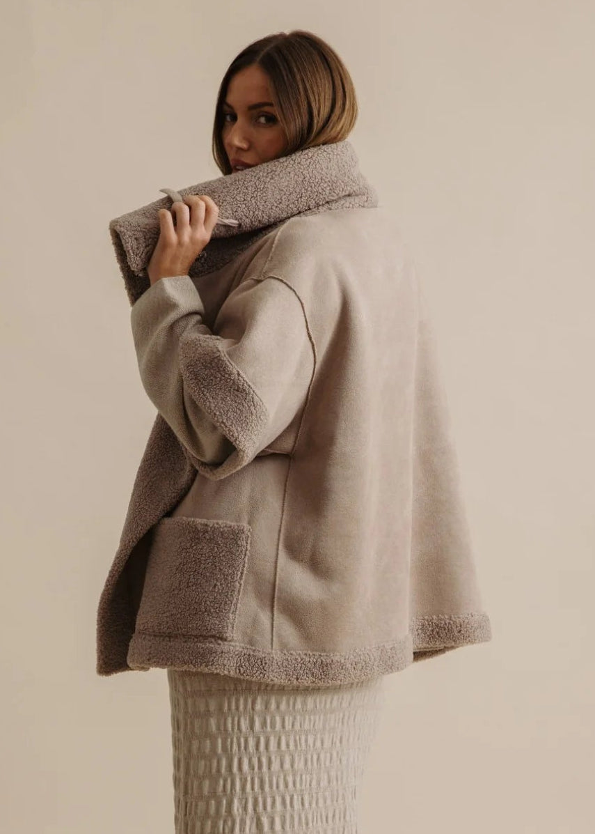 Woman wearing a beige fleece-lined jacket against a neutral background