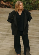Woman in a black outfit standing outdoors with a neutral background