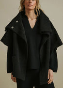 Woman wearing a black coat over a plain background