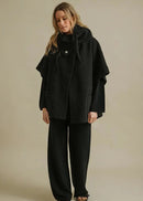 Woman wearing a black coat over a plain background