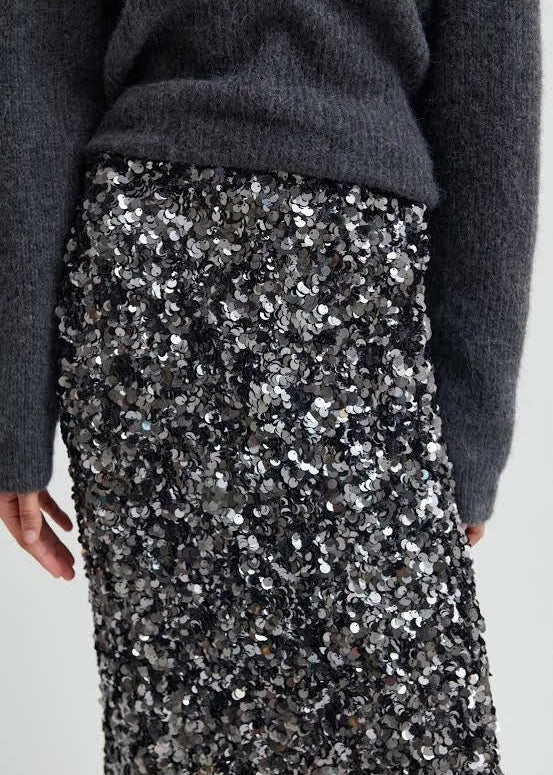 Woman wearing a grey sequin skirt on a light grey background