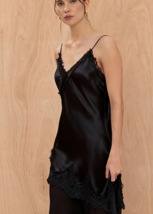 Woman wearing a black satin slip dress against a wooden background