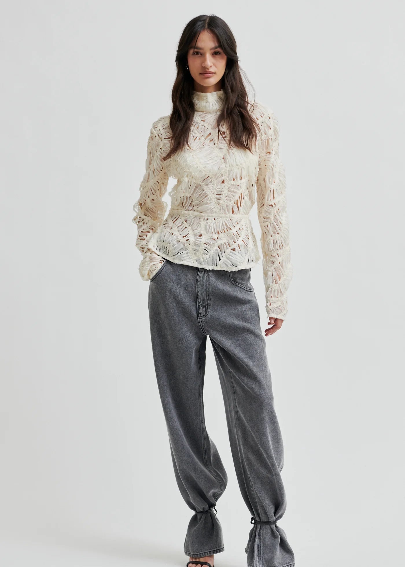 Woman wearing a textured white blouse against a plain background