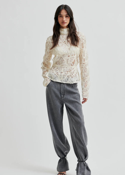 Woman wearing a textured white blouse against a plain background