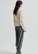Woman wearing a textured white blouse against a plain background