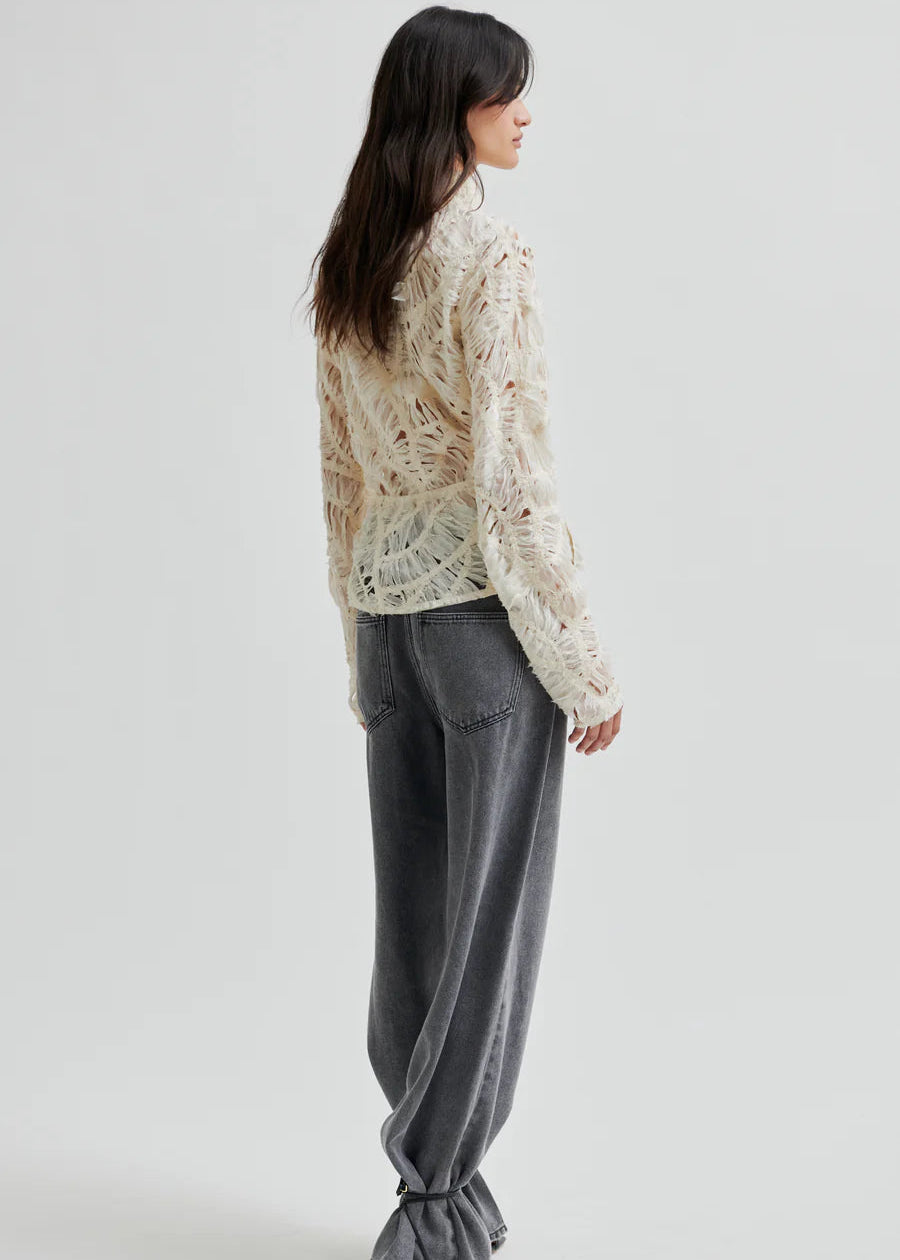 Woman wearing a textured white blouse against a plain background