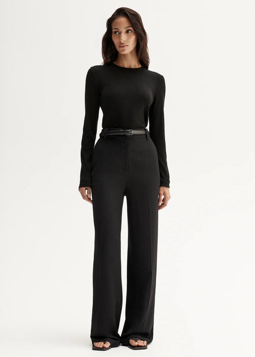 Woman wearing a black long-sleeve top and pants on a white background