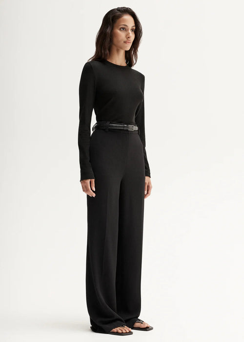 Woman wearing a black long-sleeve top against a white background