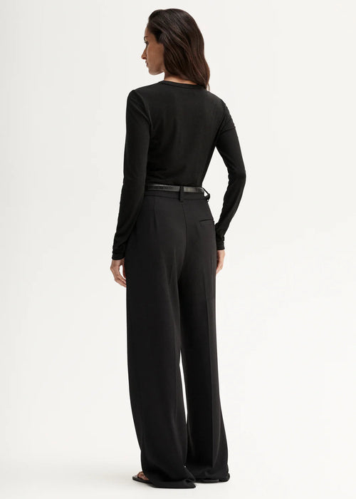 Woman wearing a black long-sleeve top against a white background