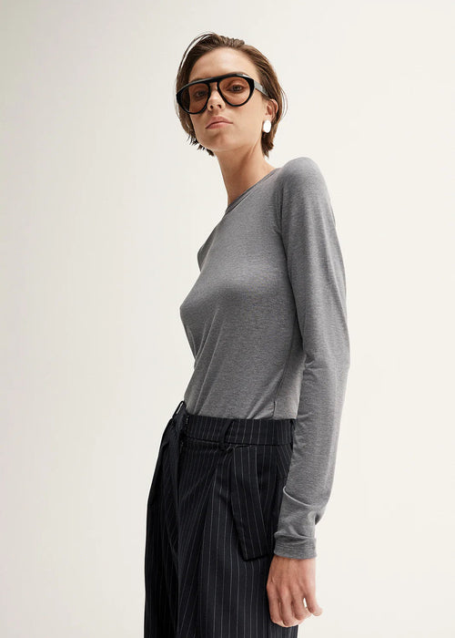 Woman wearing a gray sweater and black pinstripe pants on a white background
