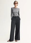 Woman wearing a grey sweater and black pinstripe pants on a white background