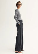Woman wearing a grey sweater and black pinstripe pants on a white background