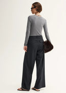 Woman wearing a grey sweater and black pinstripe pants on a white background