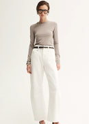 Woman wearing a grey long-sleeve top and white pants on a white background