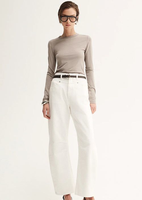 Woman wearing a grey long-sleeve top and white pants on a white background