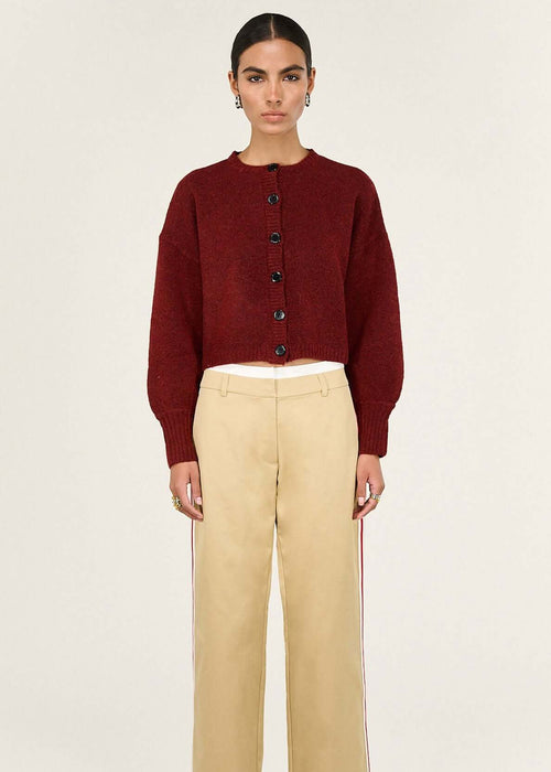 Woman wearing a burgundy cardigan and beige pants on a white background