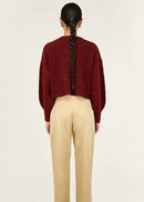 Woman wearing a burgundy cardigan and beige pants on a white background