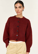 Woman wearing a burgundy cardigan and beige pants on a white background