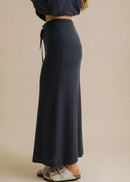 Woman wearing a long navy skirt on a beige background
