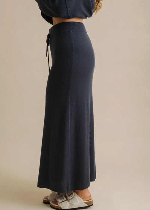 Woman wearing a long navy skirt on a beige background