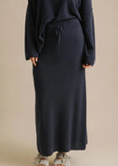 Woman wearing a long navy skirt on a beige background
