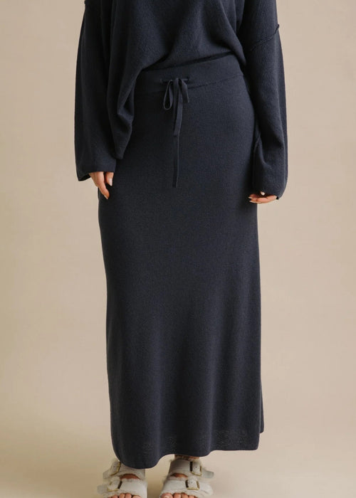 Woman wearing a long navy skirt on a beige background