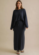 Woman wearing a long navy skirt on a beige background