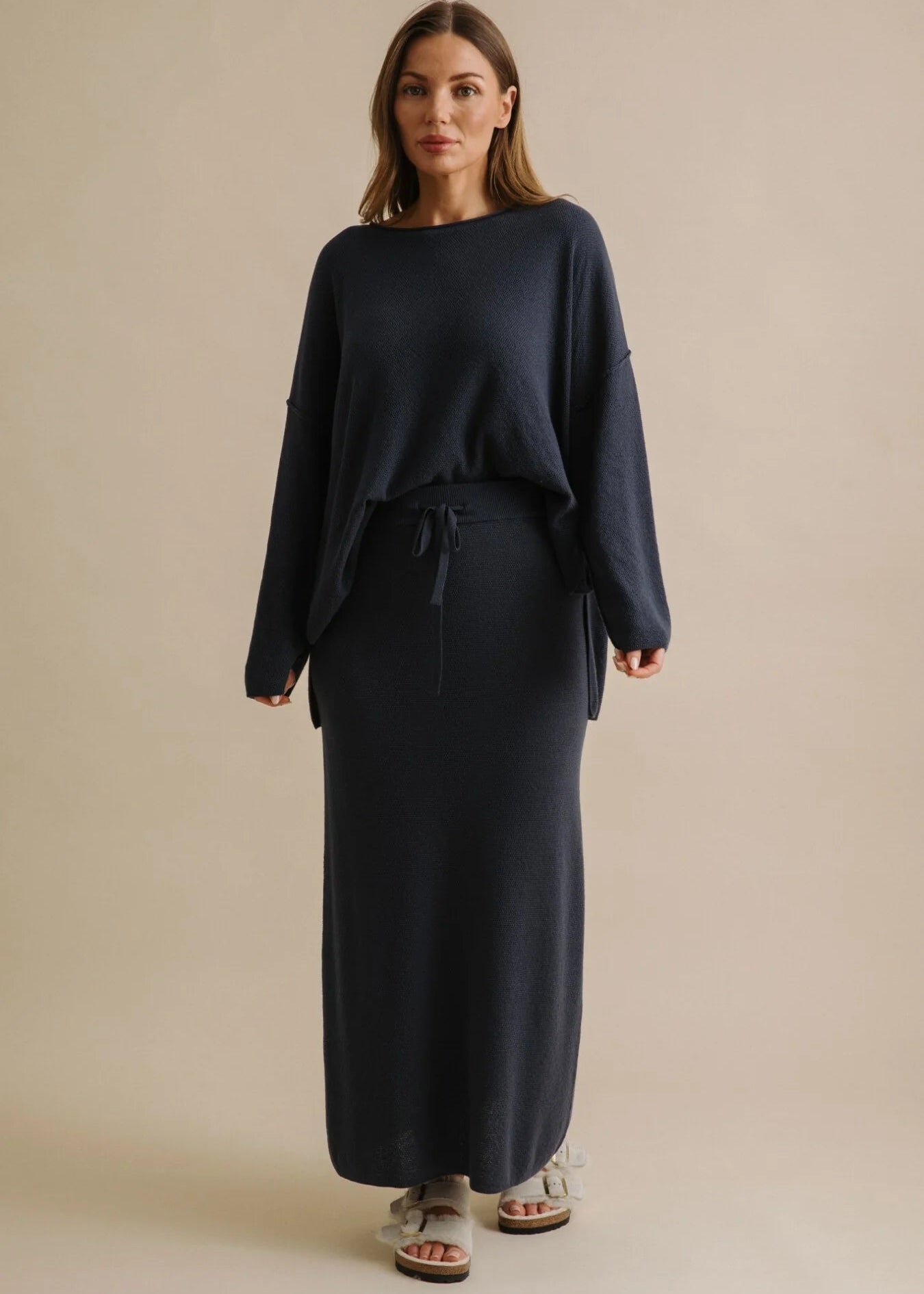 Woman wearing a long navy skirt on a beige background