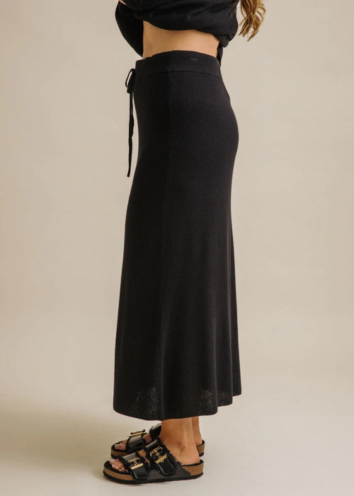 Woman wearing a black skirt with a plain background