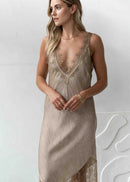 Woman wearing a beige slip dress with lace details against a white background