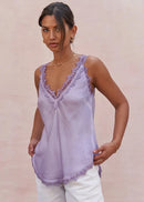 Woman wearing a light purple lace-trimmed top against a beige background